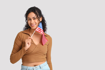 Beautiful young happy African-American woman with USA flag on white background
