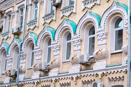 Traditional ornate facade with row of arched windows on wall of old residential building with ornamental details in Moscow, Russia. Architecture and city street background 