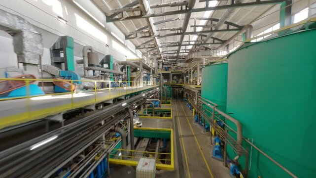 Hall with piping arrangement for production of cardboard packaging. Large bright hall of pulp and paper mill tanks for liquid material transportation