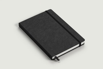 A black notebook with a black elastic closure lies on a light grey surface.