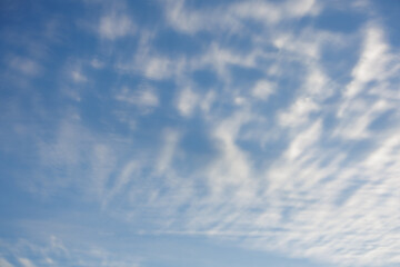 Soft wispy clouds stretch out vertically in a diagonal pattern on a light blue sky, creating a tranquil scene suitable for a background or wallpaper usage.