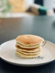 Stack of fluffy pancakes on a white plate with a simple design