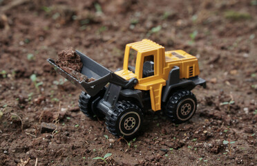 Yellow wheel loader or tractor toy on soil or ground background. construction image concept with heavy equipment.