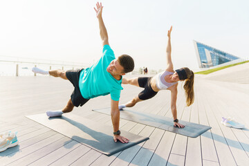 Group fitness workout on outdoor platform by the waterfront during bright daylight in summer