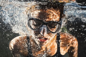Fototapeta premium Swimmer wearing goggles diving underwater with bubbles rising to surface