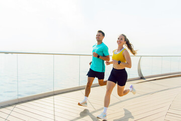 Couple enjoying a morning run along a scenic waterfront promenade on a sunny day