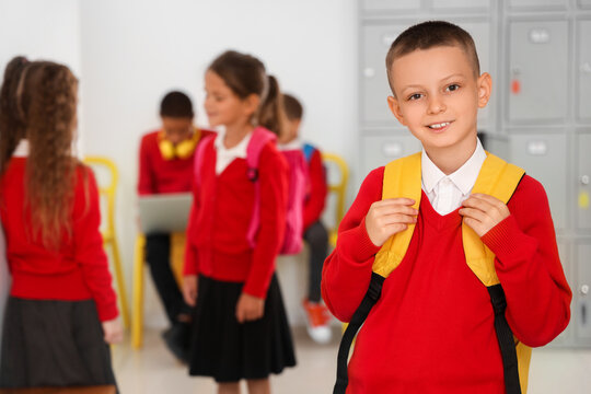 Little schoolboy with backpack at school hall