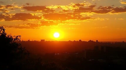 Obraz premium Fiery sunset over a city skyline, silhouettes of buildings against a vibrant orange sky.