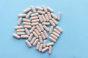 Herbal capsules on light blue background close up. Herbal medicine concept