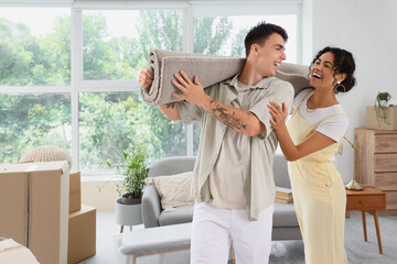 Obraz premium Young couple carrying carpet in room on moving day