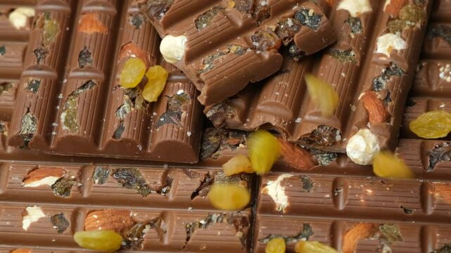 Raisins pouring on milk chocolate bars slow motion.