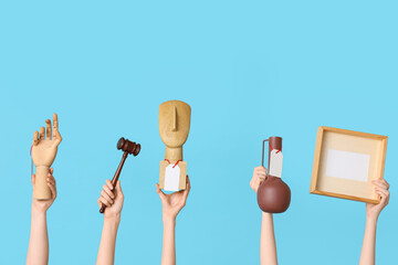 Female hands with auction gavel and antique items on blue background