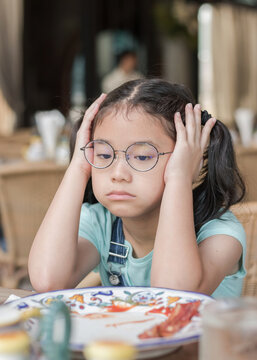 A school girl child, Asian kid, picky eater with Anorexia, Bulimia Nervosa; eating problem, avoidant restrictive food intake disorder (ARFID), losing appetite with disliked healthy food meal