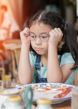 A school girl child, Asian kid, picky eater with Anorexia, Bulimia Nervosa; eating problem, avoidant restrictive food intake disorder (ARFID), losing appetite with disliked healthy food meal