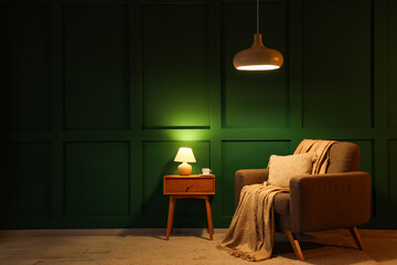 Interior of dark room with glowing lamps, armchair and table at night