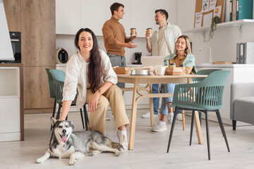 Young woman with Husky dog and her colleagues during lunch in office kitchen