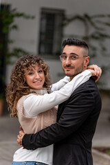 Young couple hugging each other in a city street, expressing love and happiness