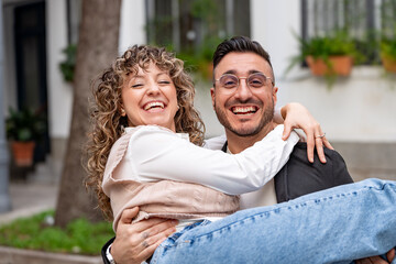 Happy couple laughing and enjoying time together as the husband holds his wife in his arms outdoors