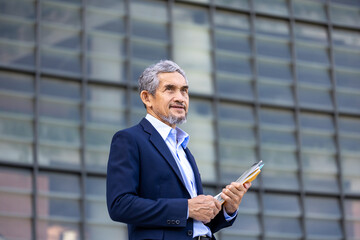 Portrait of confidence senior asian CEO businessman is holding document and digital tablet at his modern office for market leader, manager, executive corporate and millionaire concept