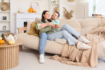 Fototapeta premium Happy young couple with cup of tea sitting at home on autumn day
