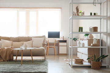 Interior of living room with shelving unit, sofa, coffee table and workplace