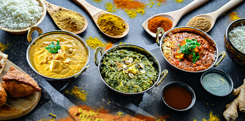 Composition with Indian dishes: madras paneer, palak paneer and shahi paneer with basmati rice served in original indian karahi pots