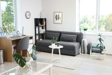 Interior of living room with modern grey sofa, coffee table and workspace