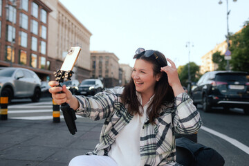 Vlogger traveler woman recording video on phone camera on Khreshchatyk in Kyiv, Ukraine. Gen Z Plus size girl influencer shooting social media stories on the street