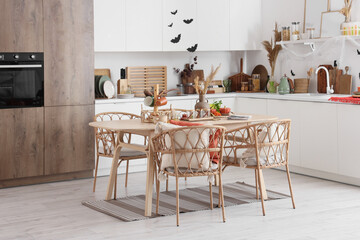 Interior of light kitchen decorated for Halloween with white counters and dining table
