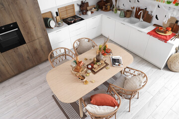 Interior of light kitchen decorated for Halloween with white counters and dining table