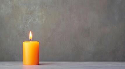 A lit orange candle stands on a smooth surface, casting a warm glow against a muted gray background.