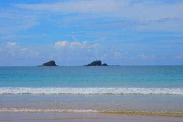 Dwie małe wyspy widoczne w oddali. Plaża i dwie tropikalne wyspy w tle.