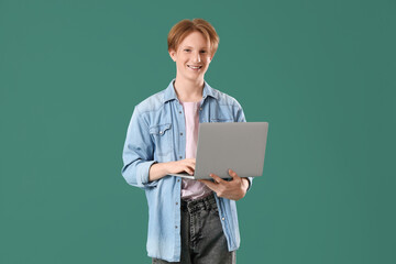 Male student using laptop on green background