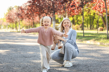 Fototapeta premium Cute little girl and her mother with toy bear in park on autumn day