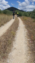 Obraz premium Parte do Caminho de Santiago de Compostela Português, seguindo por estrada rural de terra com montanha ao fundo, e céu azul.
