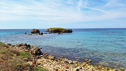 The rocky coast with its crystalline water. Village of Sant Tomas, Alaior, Menorca, Balearic Islands, Spain.
