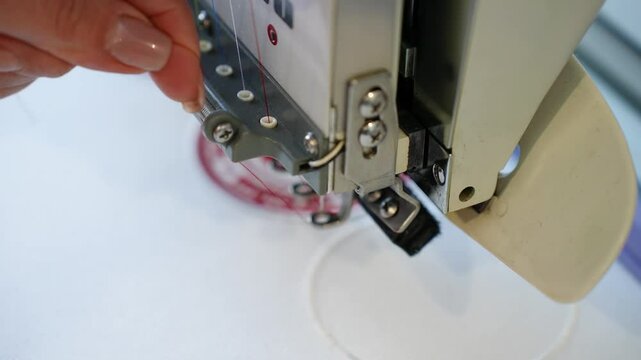Embroidery machine in the process of embroidering company logo on uniform in textile industry in garment factories. Weaving machine for garment industry. Sewing workshop or garment factory.