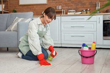 Pretty young woman with rag and sprayer cleaning floor at home