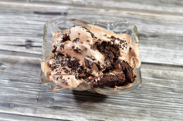 Chocolate ice cream with brownies cake and chocolate pieces and sauce on chocolate brownies,...
