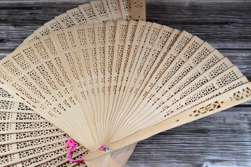Wooden handheld fan, hand fan is a broad, flat surface that is waved back and forth to create an airflow, work by utilizing the concept of thermodynamics, increase the evaporation rate of sweat © Tamer