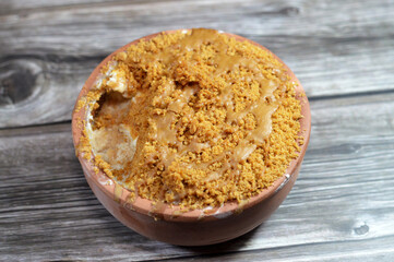 Egyptian bread pudding topped with biscuits butter spread, milk in bowl pottery casserole made of milk, Egyptian bread roqaq preparing a baked traditional Arabic Eastern dessert cuisine called Om Ali