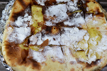 Icing powdered sugar on a cushioned pies or Feteer Meshaltet cushion like pie flaky Egyptian layered pastry of many thin layers of dough and ghee filled and stuffed with vanilla custard