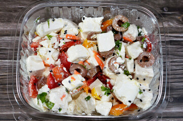 Greek salad or horiatiki, made with pieces of tomatoes, cucumbers, onion, feta cheese, parsley, colorful bell peppers and olives, dressed with salt, Greek oregano, lemon juice and olive oil