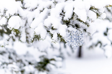 Silver crystal snowflake ornament hanging on a snowy tree branch. Winter background.
