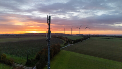 5G Tower and Wind Turbines During Vibrant Countryside Sunset