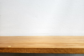 Wooden Shelf over White Stucco Wall Background with Light Beam at the Center