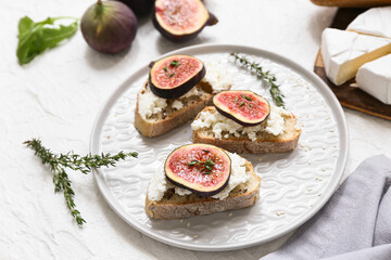 Plate of delicious fig bruschetta with ricotta cheese on white background, closeup