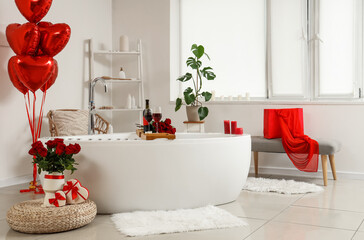 Interior of light bathroom decorated for Valentine's Day with bathtub and balloons