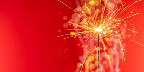 Beautiful glowing sparklers on colored background. Colorful sparklers sparkling against vibrant red...