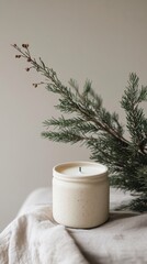Minimalist candle in ceramic jar next to pine branches on textured cloth. cozy and natural decor concept